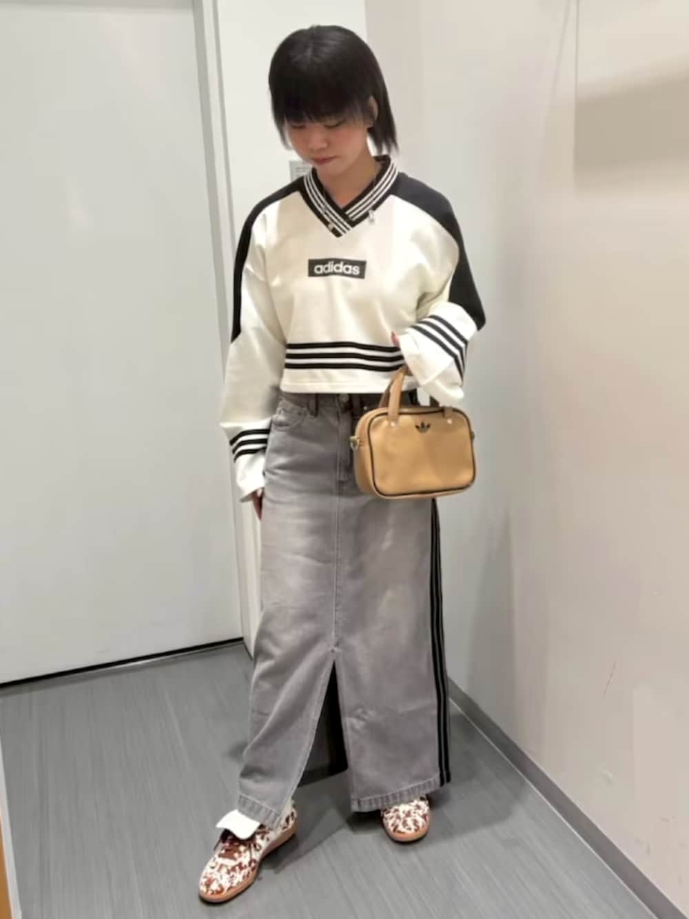 ホワイト系のスウェット、グレー系のデニムスカート、ベージュ系のショルダーバッグを着用したレディースの夏コーディネートの2枚目の写真