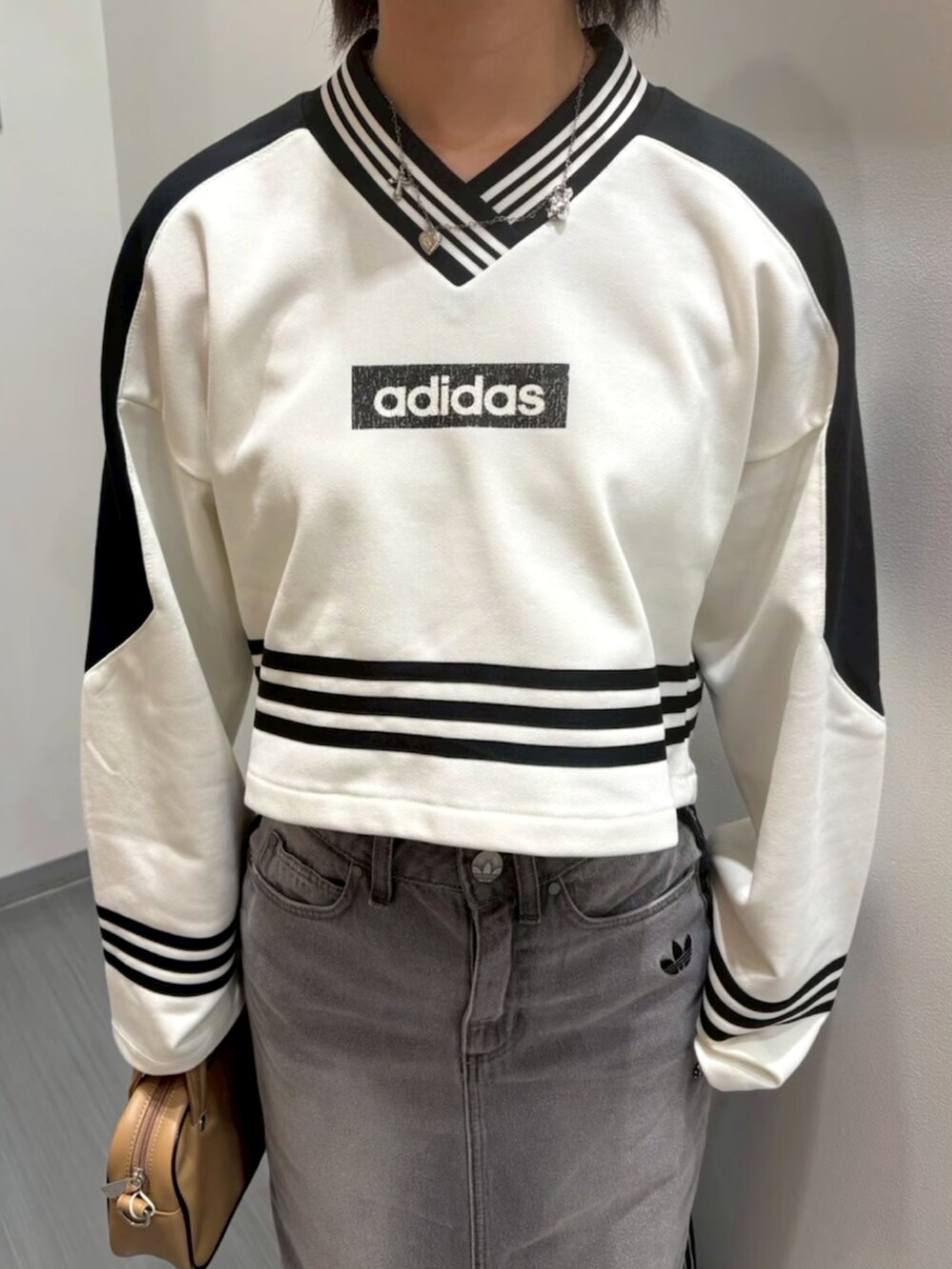 ホワイト系のスウェット、グレー系のデニムスカート、ベージュ系のショルダーバッグを着用したレディースの夏コーディネートの3枚目の写真