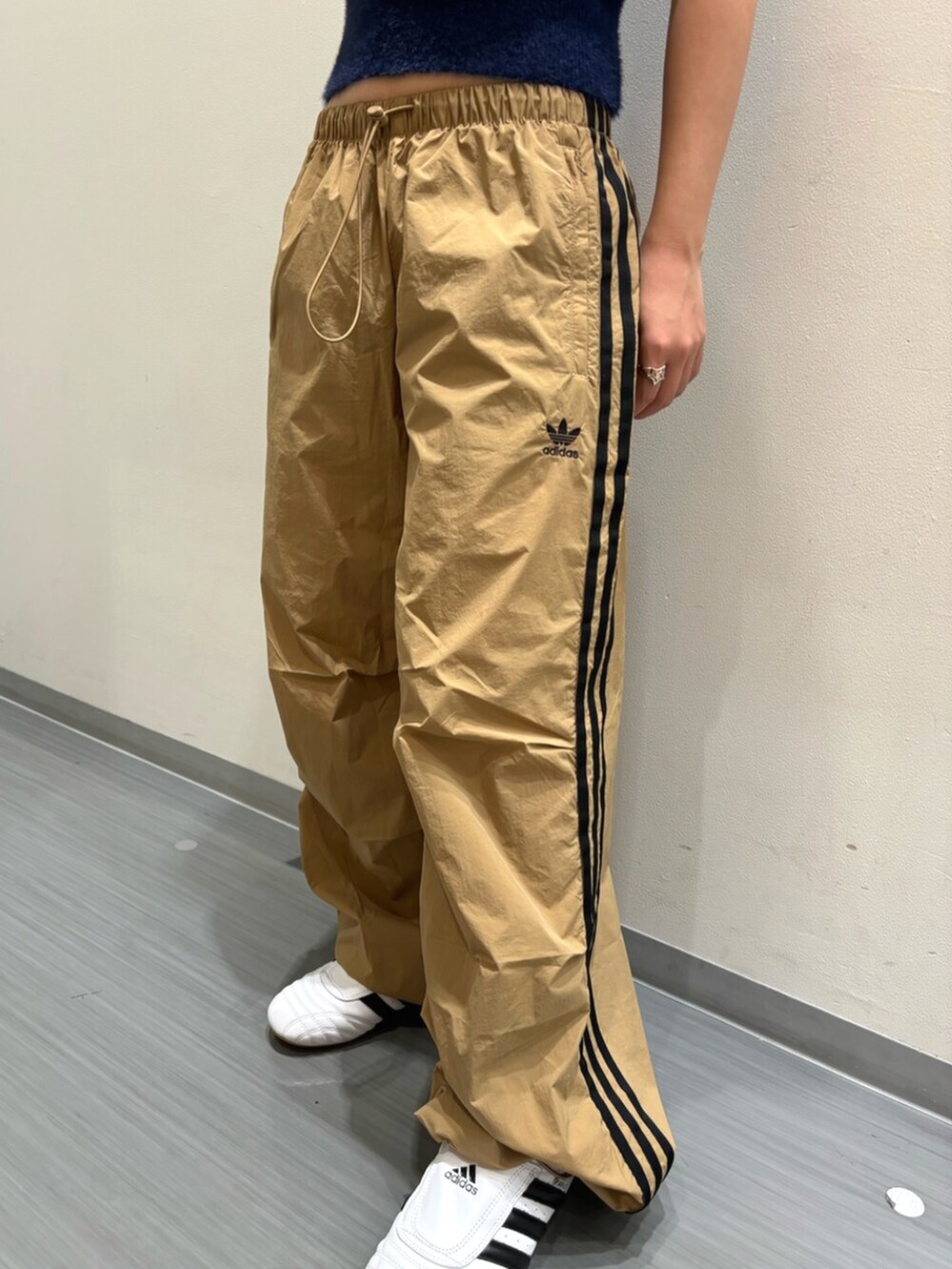 ブルー系のベスト、ブラック系のショルダーバッグ、ホワイト系のシューズを着用したレディースの秋コーディネートの5枚目の写真