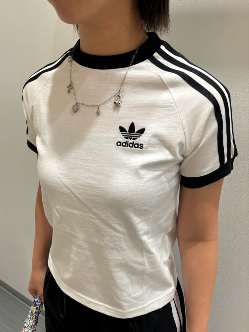 ホワイト系のTシャツ/カットソー、ホワイト系のショルダーバッグ、ブラック系のスウェットパンツを着用したレディースの夏コーディネートの2枚目の写真