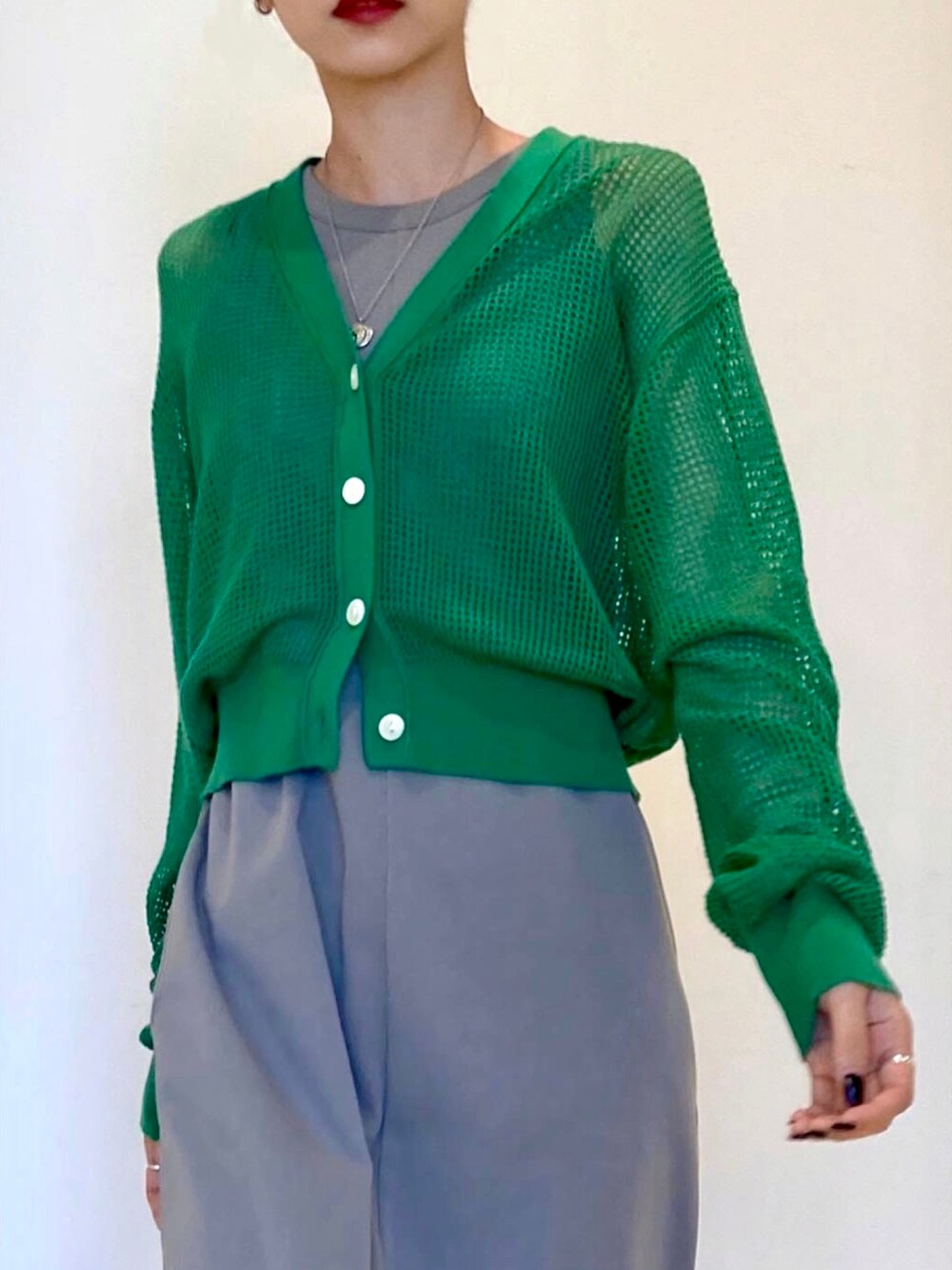 グレー系のワンピース、グリーン系のカーディガン/ボレロを着用したレディースの春コーディネートの3枚目の写真