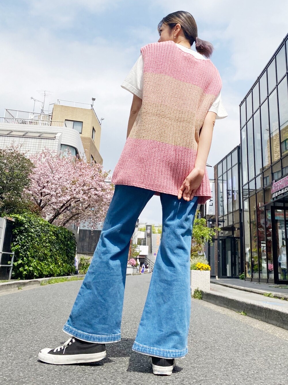 ブラック系のスニーカー、ブルー系のデニムパンツ、ピンク系のベストを着用したレディースの春コーディネートの2枚目の写真