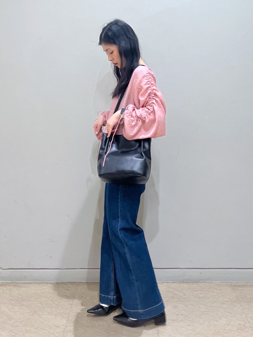 ブルー系のデニムパンツ、ピンク系のカーディガン/ボレロ、ブラック系のショルダーバッグを着用したレディースの春コーディネートの2枚目の写真