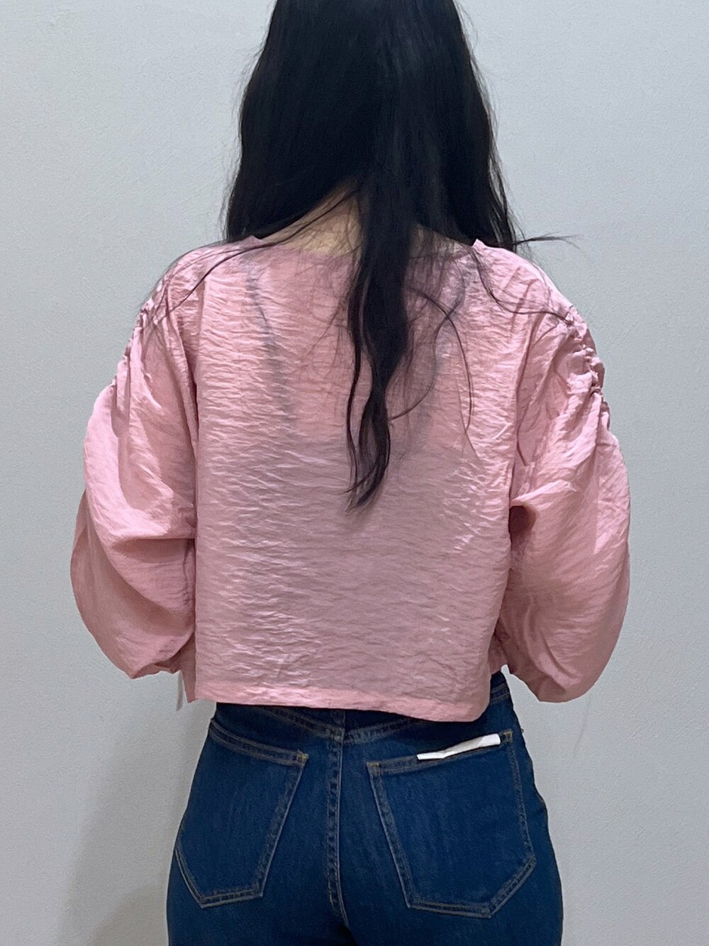 ブルー系のデニムパンツ、ピンク系のカーディガン/ボレロ、ブラック系のショルダーバッグを着用したレディースの春コーディネートの3枚目の写真