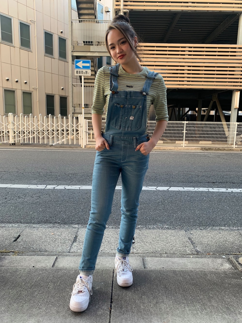 グリーン系のトップス、ブルー系のサロペット/オーバーオール、ホワイト系のスニーカーを着用したレディースの春コーディネートの2枚目の写真