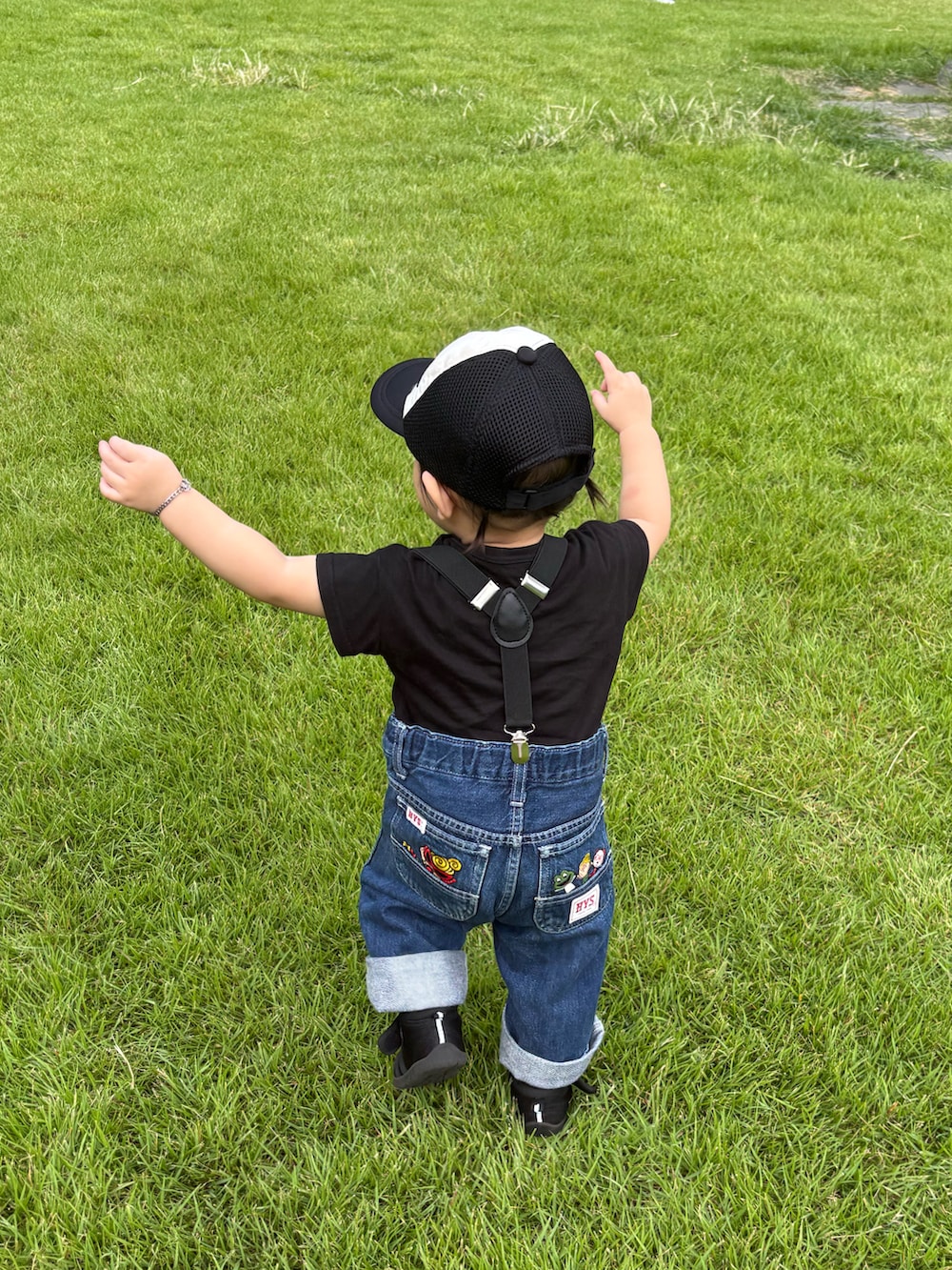 ブルー系のデニムパンツ、ホワイト系のキャップを着用したキッズの秋コーディネートの2枚目の写真