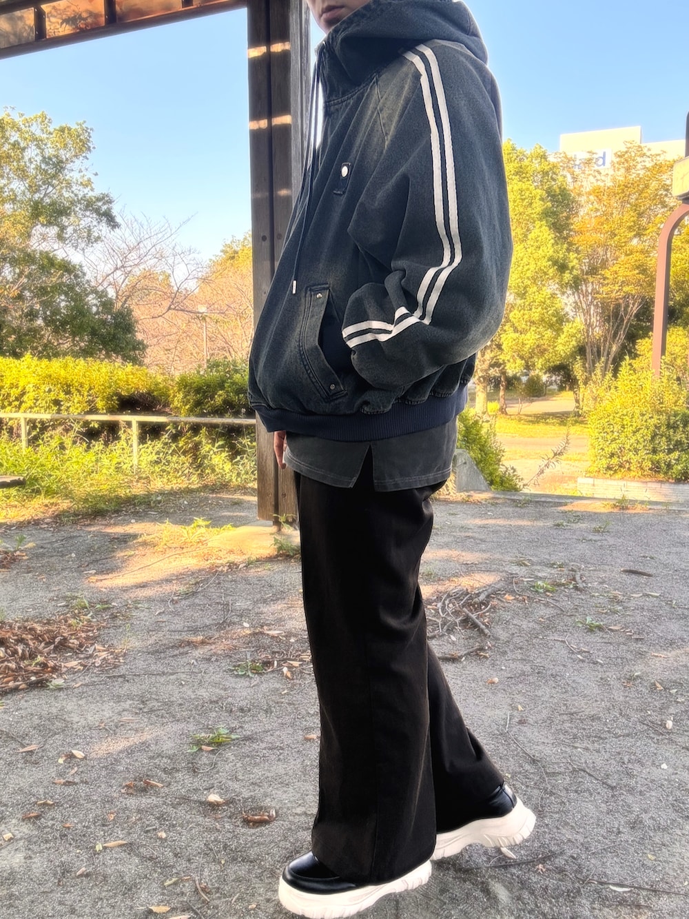 ブラック系のスラックス、ブラック系のスニーカー、ブルー系のタンクトップを着用したメンズの秋コーディネートの2枚目の写真