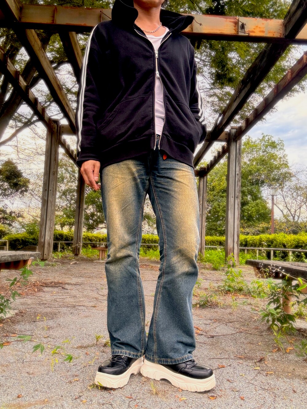 ブラック系のパーカー、ブルー系のデニムパンツ、ブラック系のスニーカーを着用したメンズの秋コーディネートの2枚目の写真