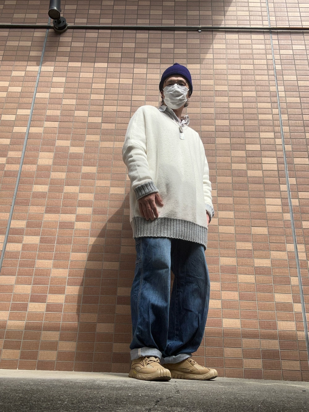 ブルー系のデニムパンツ、ベージュ系のスニーカー、ホワイト系のニット/セーターを着用したメンズの春コーディネートの4枚目の写真