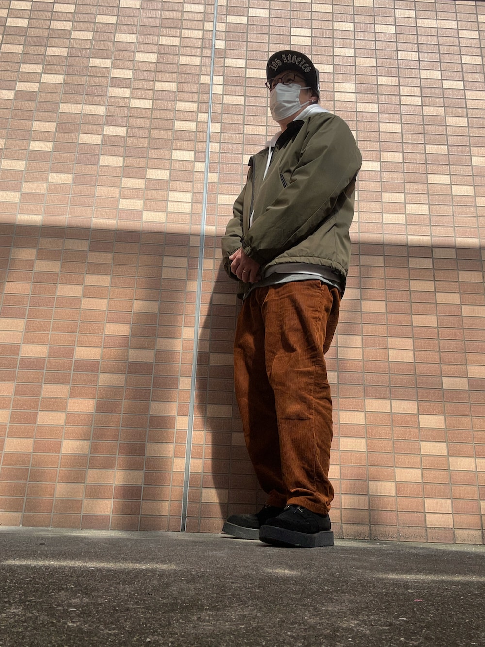 ホワイト系のパーカー、ブラウン系のパンツ、ブラック系のその他シューズを着用したメンズの春コーディネートの2枚目の写真