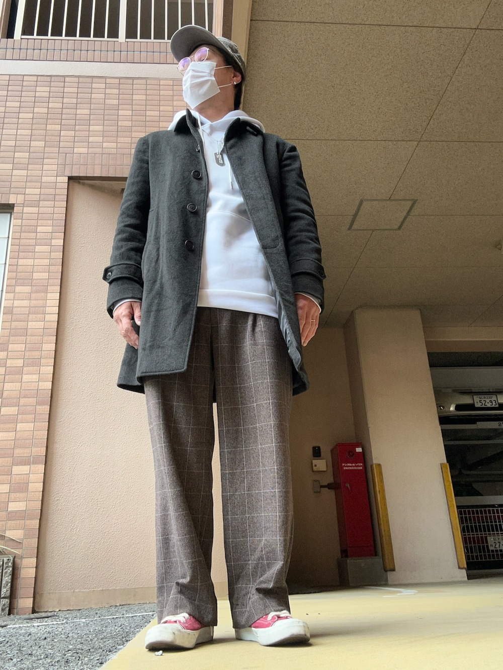 ホワイト系のパーカー、グレー系のチェスターコート、ブラウン系のスラックスを着用したメンズの冬コーディネートの3枚目の写真