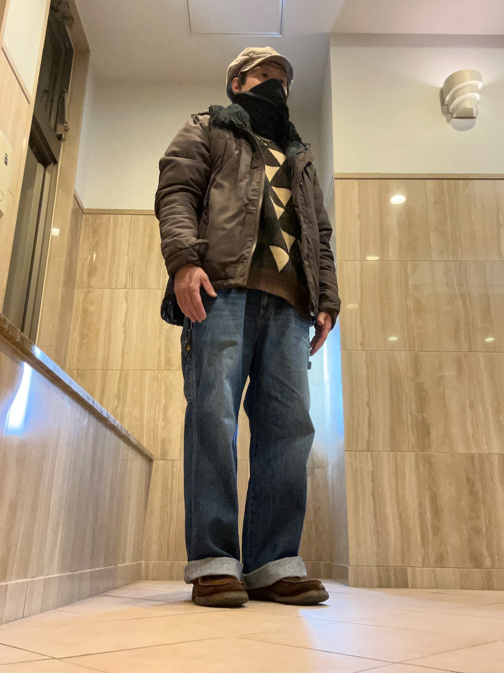 ブルー系のデニムパンツ、ブラウン系のブーツ、ブラウン系のマウンテンパーカーを着用したメンズの冬コーディネートの2枚目の写真