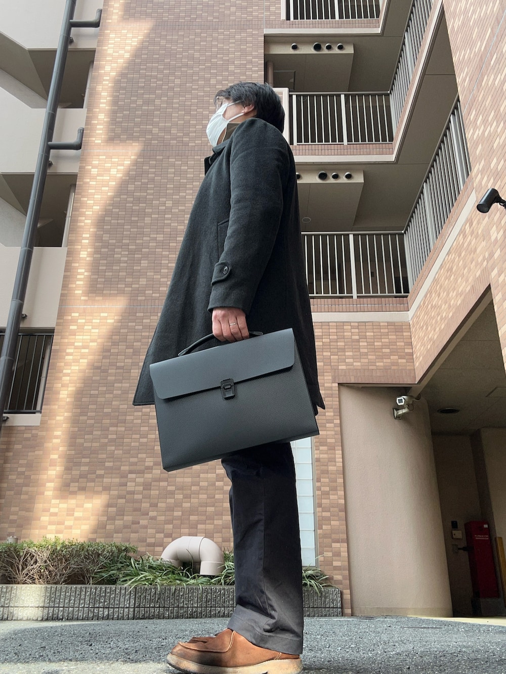 ホワイト系のニット/セーター、グレー系のチェスターコート、ブラック系のスラックスを着用したメンズの冬コーディネートの2枚目の写真