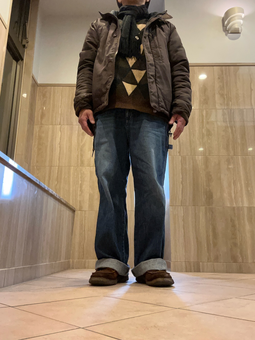 ブルー系のデニムパンツ、ブラウン系のブーツ、ブラウン系のマウンテンパーカーを着用したメンズの冬コーディネートの3枚目の写真