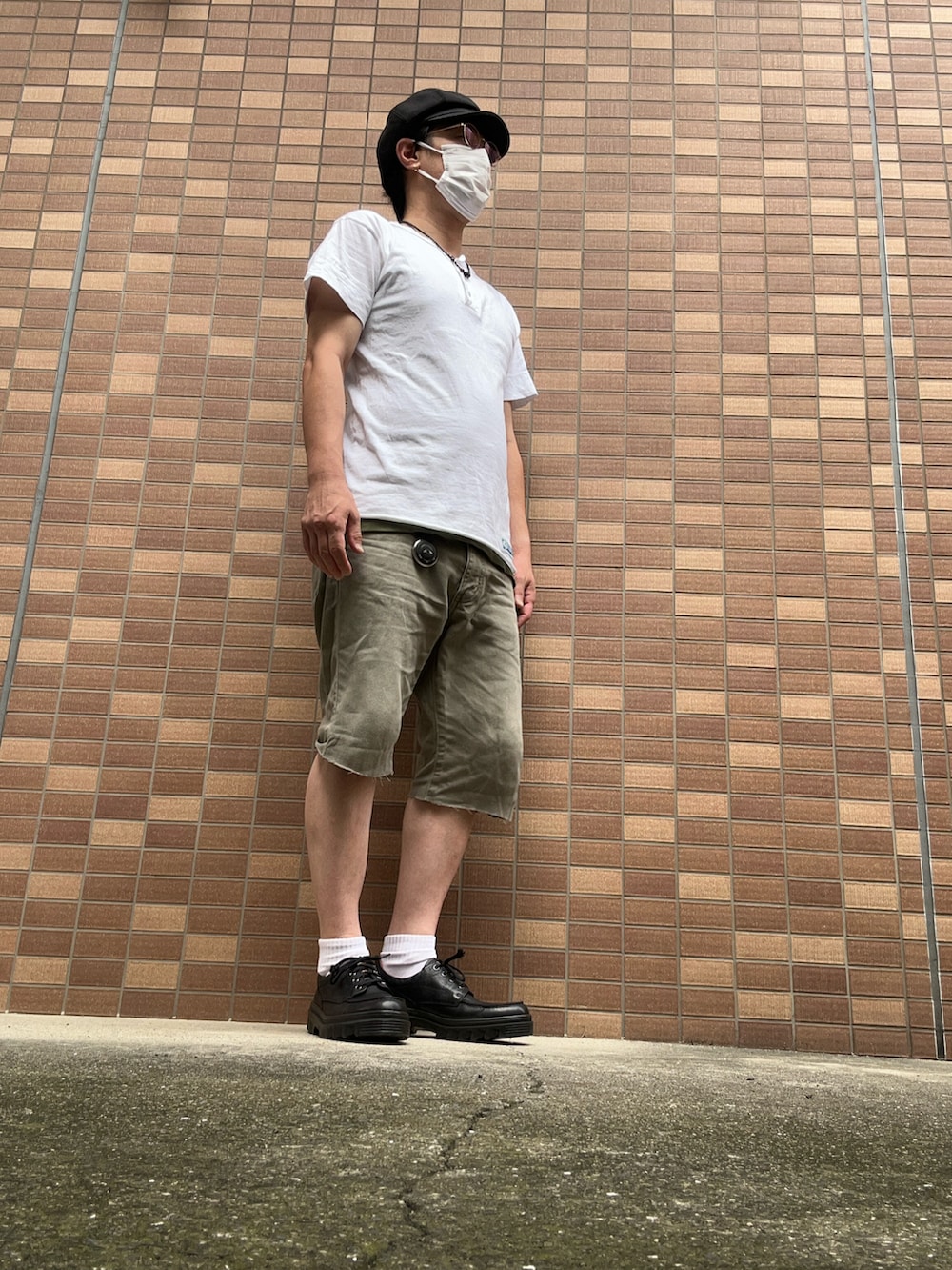 ホワイト系のポロシャツ、グリーン系のパンツ、ブラック系のその他シューズを着用したメンズの夏コーディネートの2枚目の写真