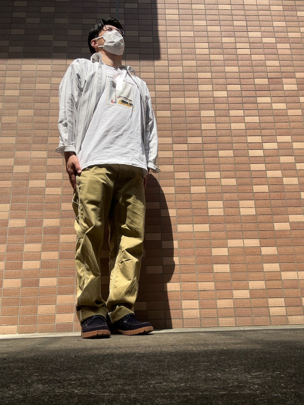 ホワイト系のTシャツ/カットソー、ベージュ系のチノパンツ、ブルー系のモカシン/デッキシューズを着用したメンズの春コーディネートの4枚目の写真