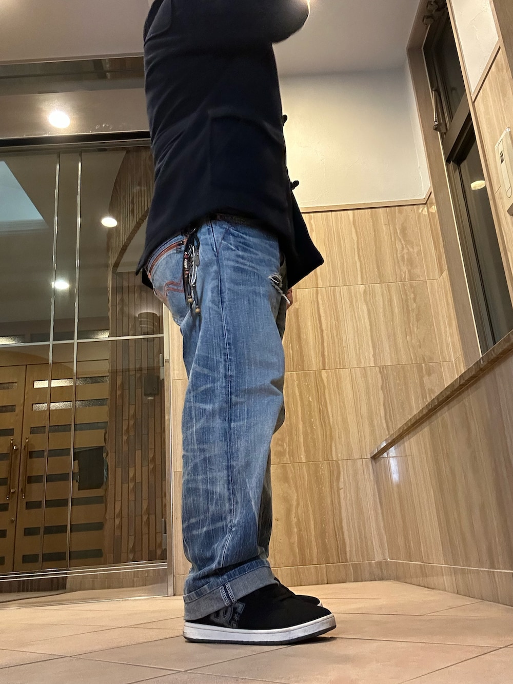 ブラック系のダッフルコート、ブルー系のデニムパンツ、ブラック系のスニーカーを着用したメンズの冬コーディネートの2枚目の写真