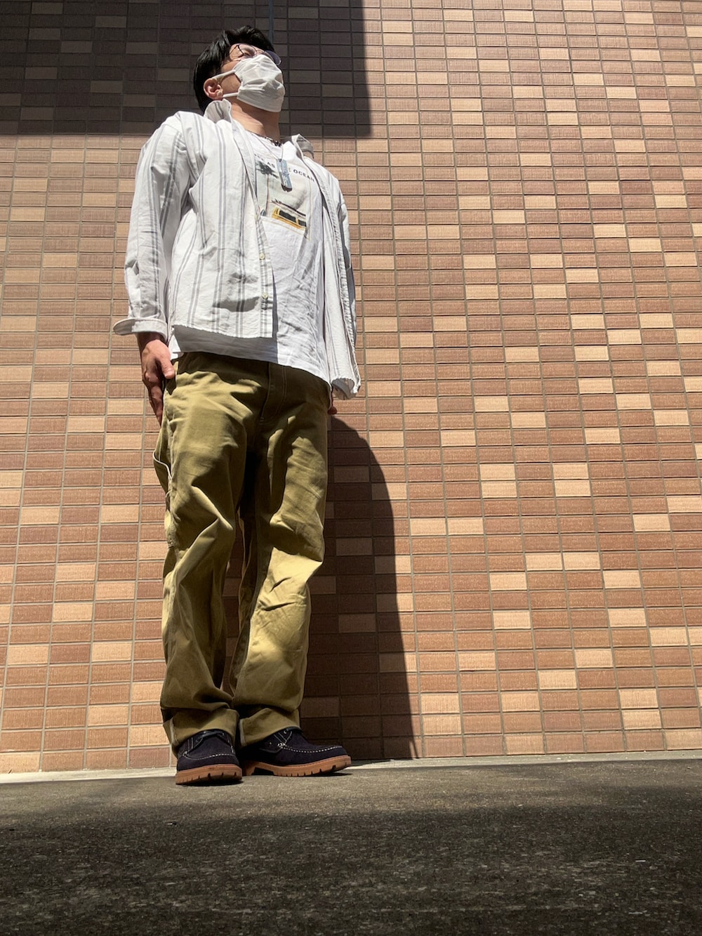 ホワイト系のTシャツ/カットソー、ベージュ系のチノパンツ、ブルー系のモカシン/デッキシューズを着用したメンズの春コーディネートの3枚目の写真