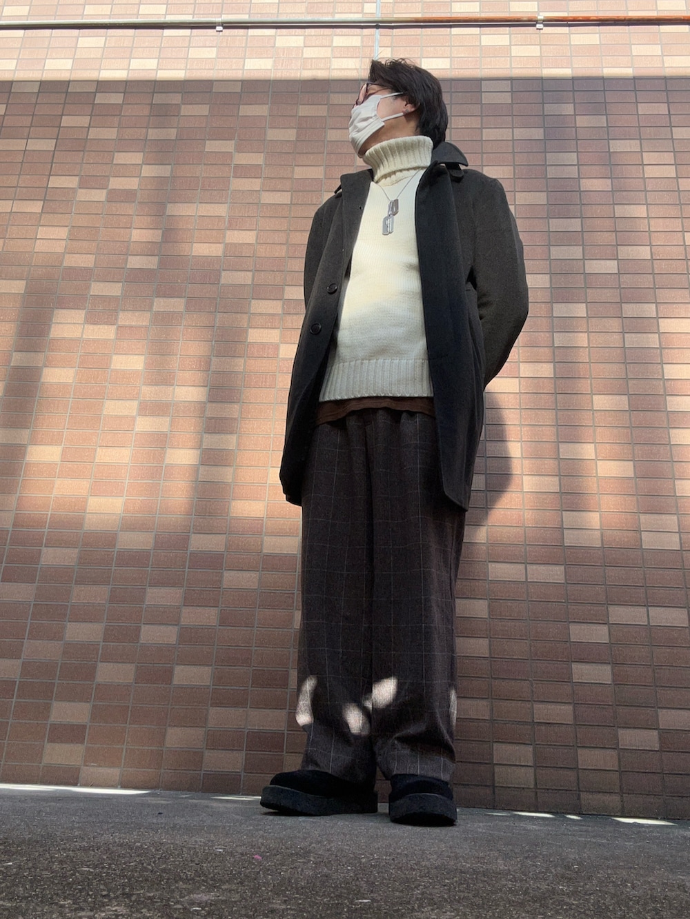 ホワイト系のニット/セーター、グレー系のニット/セーター、ブラウン系のスラックスを着用したメンズの冬コーディネートの2枚目の写真