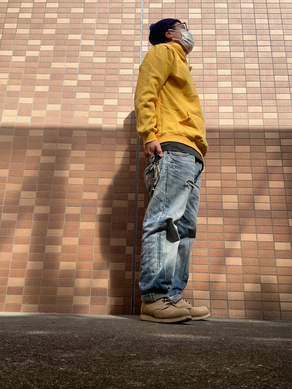 ベージュ系のブーツ、ブルー系のデニムパンツ、イエロー系のパーカーを着用したメンズの冬コーディネートの2枚目の写真