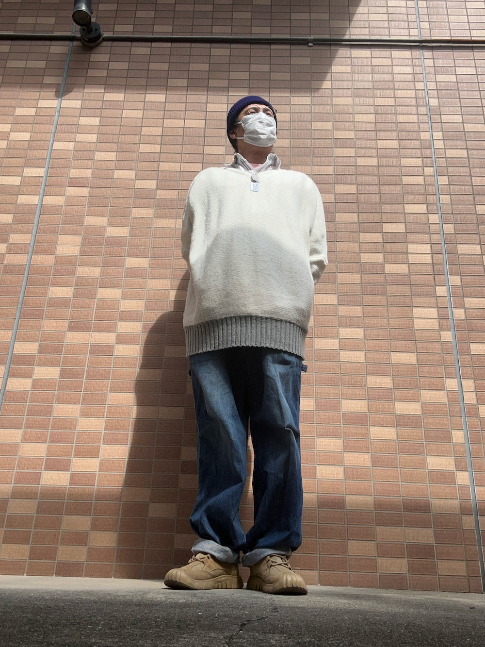 ブルー系のデニムパンツ、ベージュ系のスニーカー、ホワイト系のニット/セーターを着用したメンズの春コーディネートの3枚目の写真