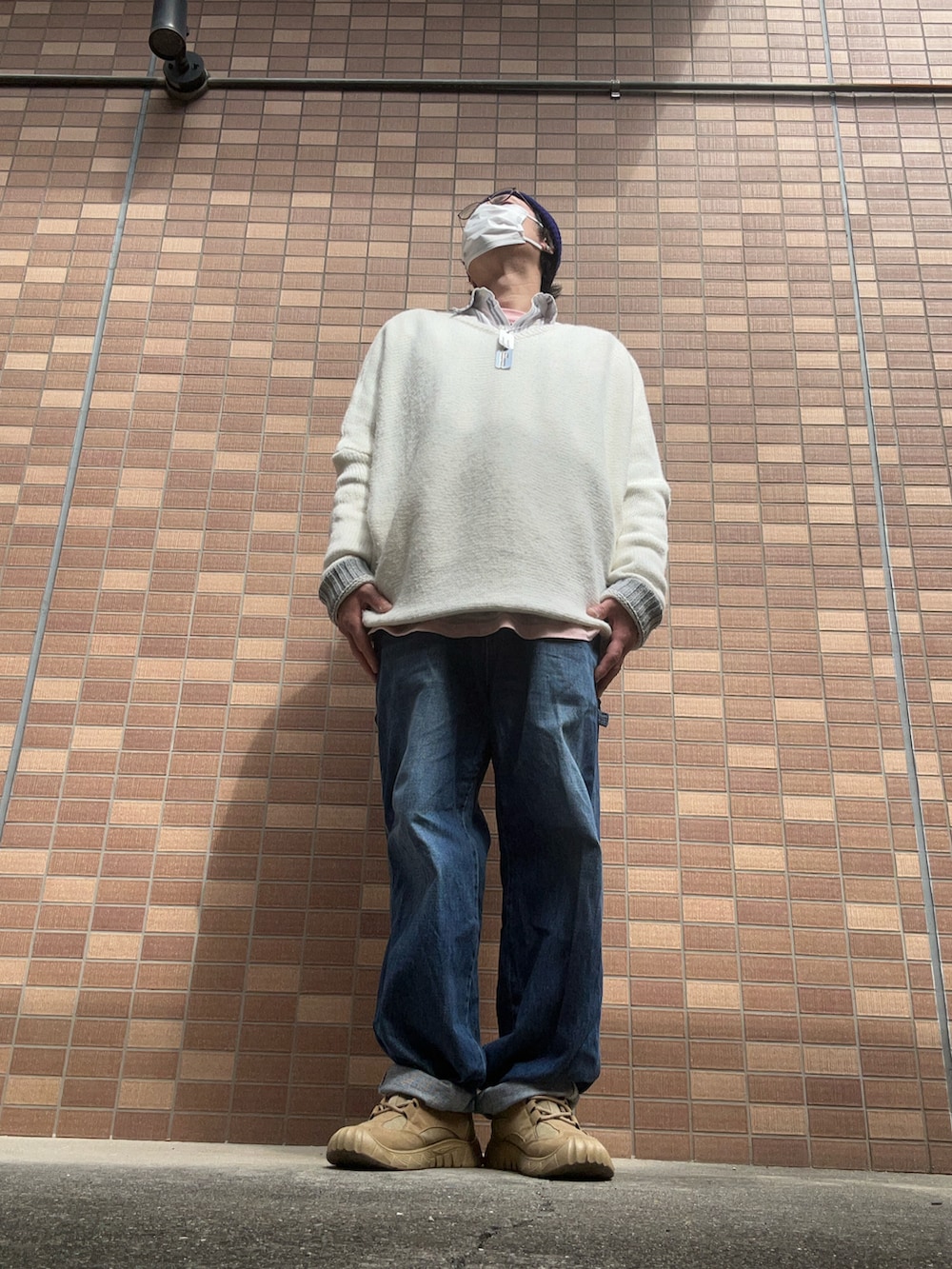 ブルー系のデニムパンツ、ベージュ系のスニーカー、ホワイト系のニット/セーターを着用したメンズの春コーディネートの5枚目の写真