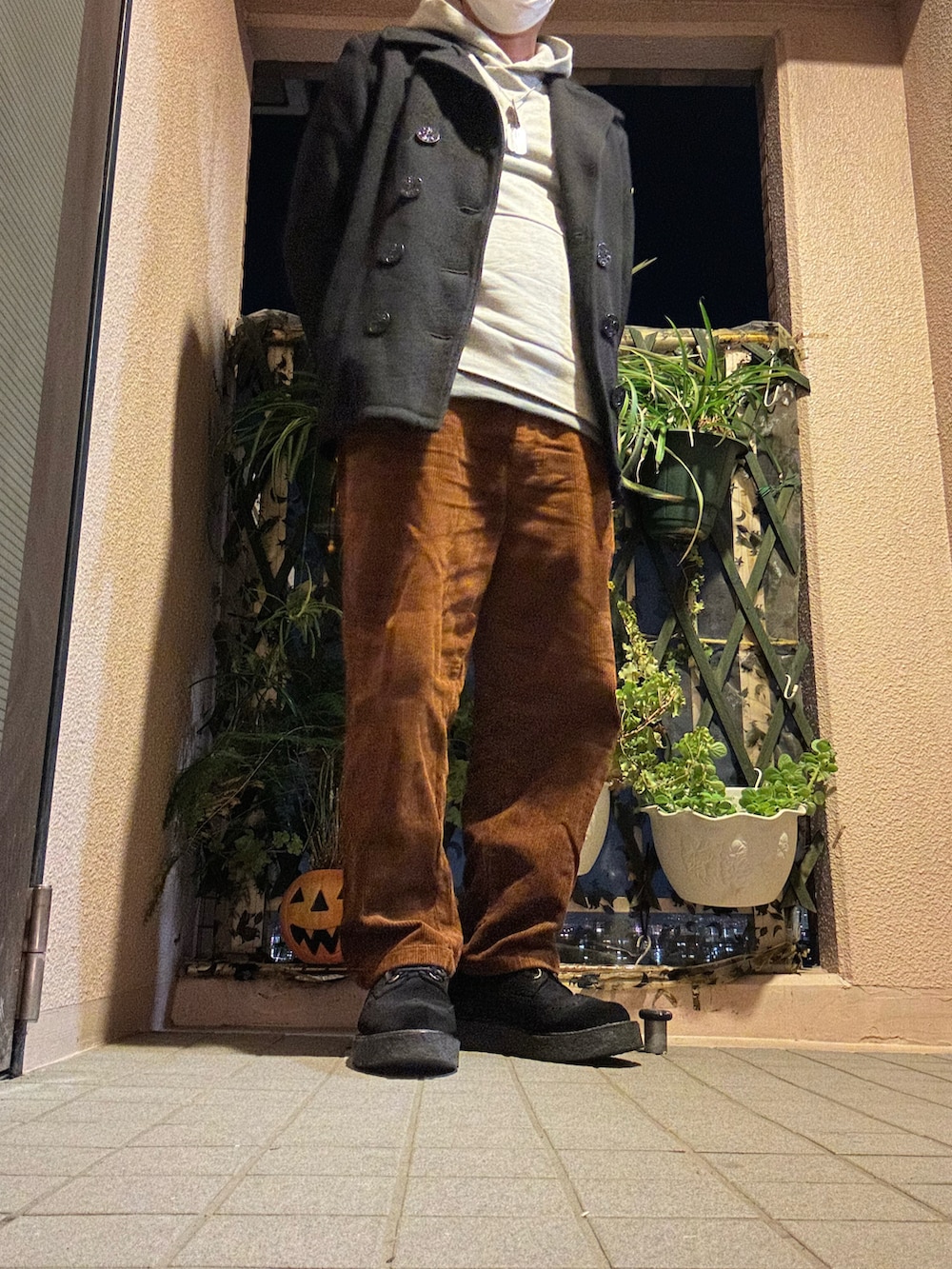 ブラウン系のパンツ、グレー系のパーカー、ブラック系のピーコートを着用したメンズの冬コーディネートの2枚目の写真