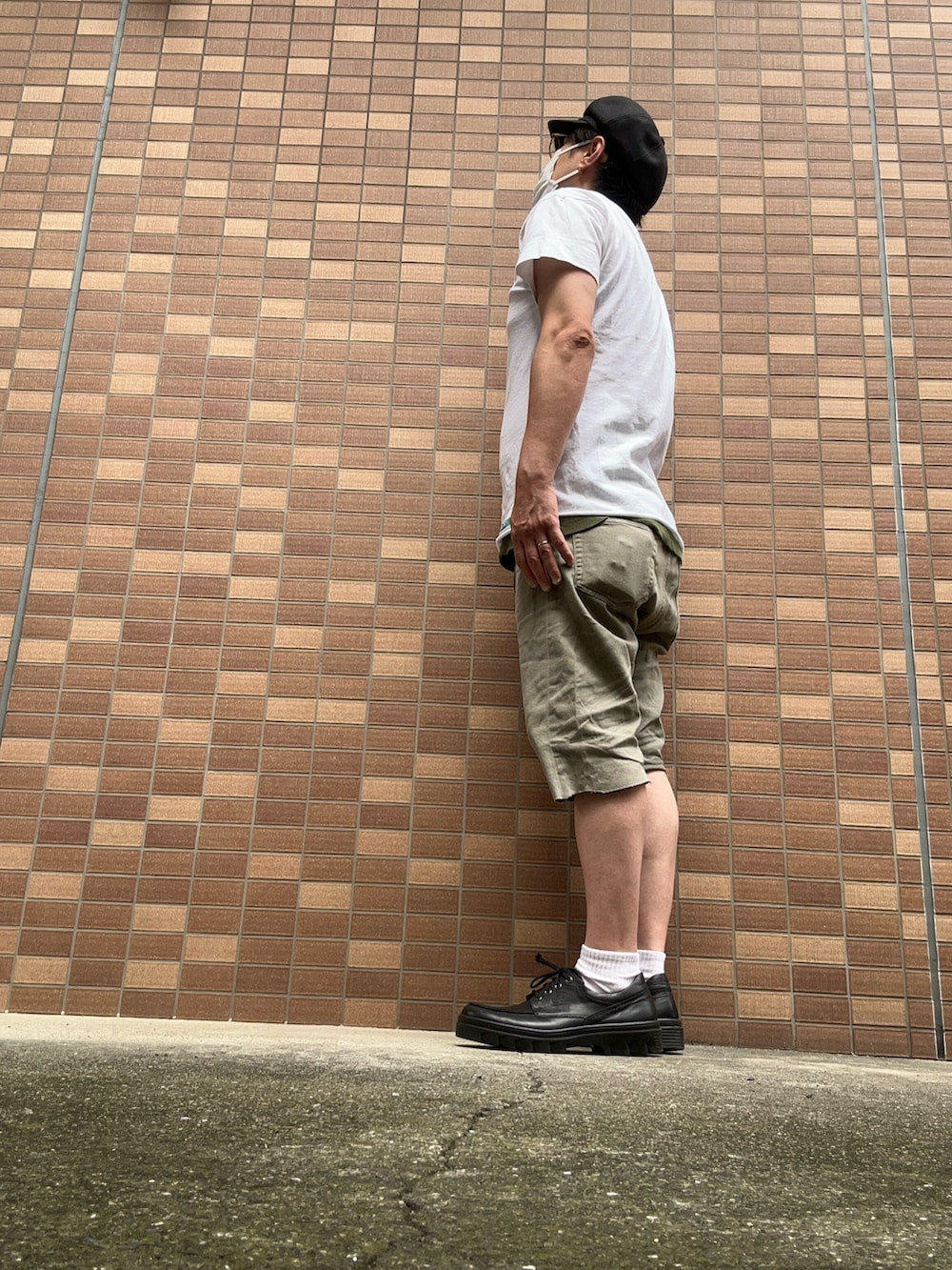 ホワイト系のポロシャツ、グリーン系のパンツ、ブラック系のその他シューズを着用したメンズの夏コーディネートの3枚目の写真