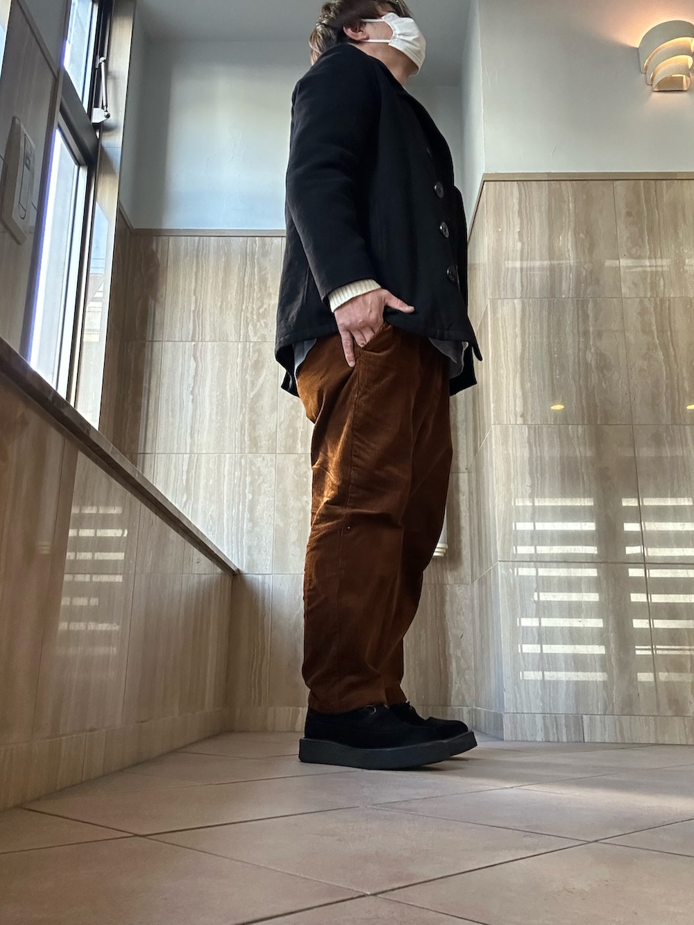 ホワイト系のニット/セーター、ブラック系のピーコート、ブラウン系のパンツを着用したメンズの冬コーディネートの2枚目の写真