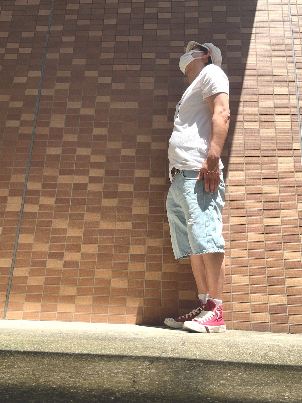 ブルー系のデニムパンツ、レッド系のスニーカー、ホワイト系のTシャツ/カットソーを着用したメンズの夏コーディネートの4枚目の写真