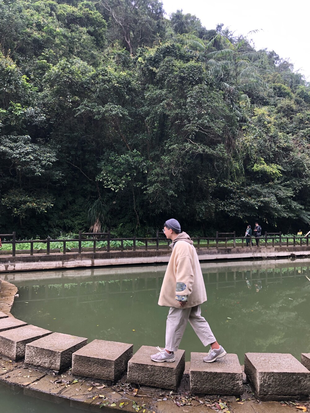 ブラウン系のパーカー、ベージュ系のチノパンツ、グレー系のスニーカーを着用したメンズの春コーディネートの2枚目の写真