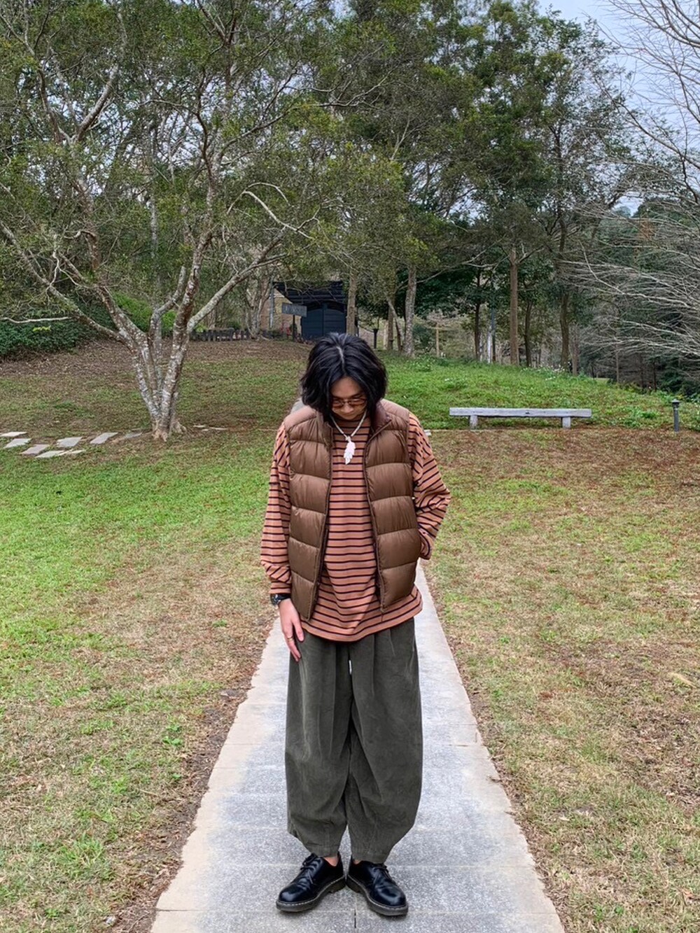 グリーン系のその他パンツ、ブラウン系のダウンベスト、オレンジ系のトップスを着用したメンズの冬コーディネートの2枚目の写真