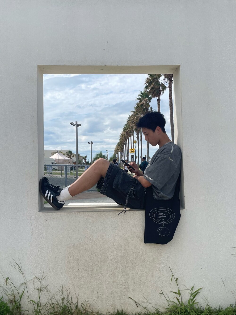 ブラック系のスニーカー、ブラック系のデニムパンツ、ブラック系のトートバッグを着用したメンズの秋コーディネートの2枚目の写真