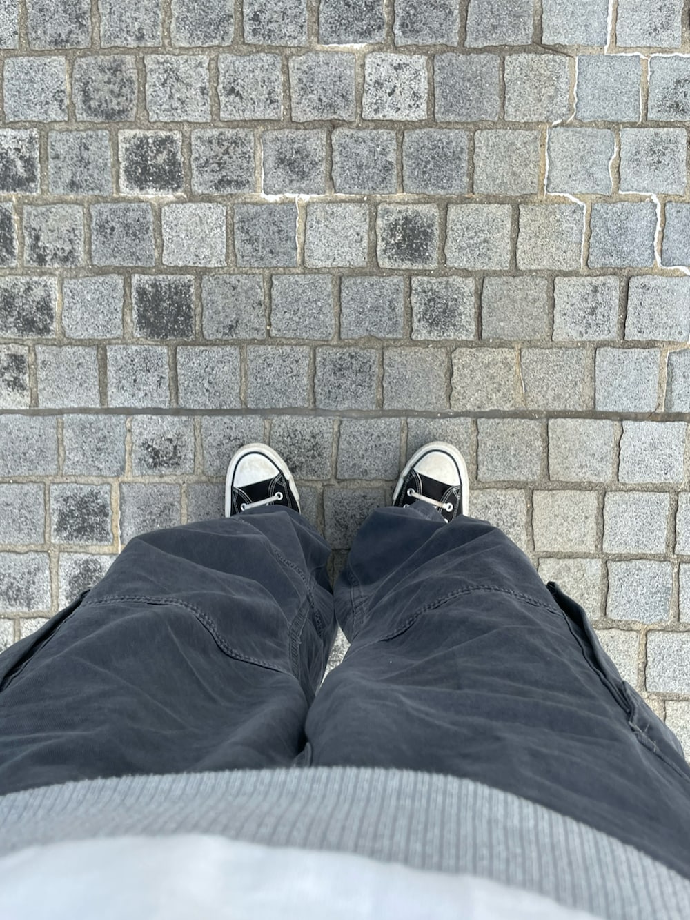 ブラック系のスニーカー、グレー系のカーゴパンツ、ホワイト系のベストを着用したメンズの春コーディネートの2枚目の写真