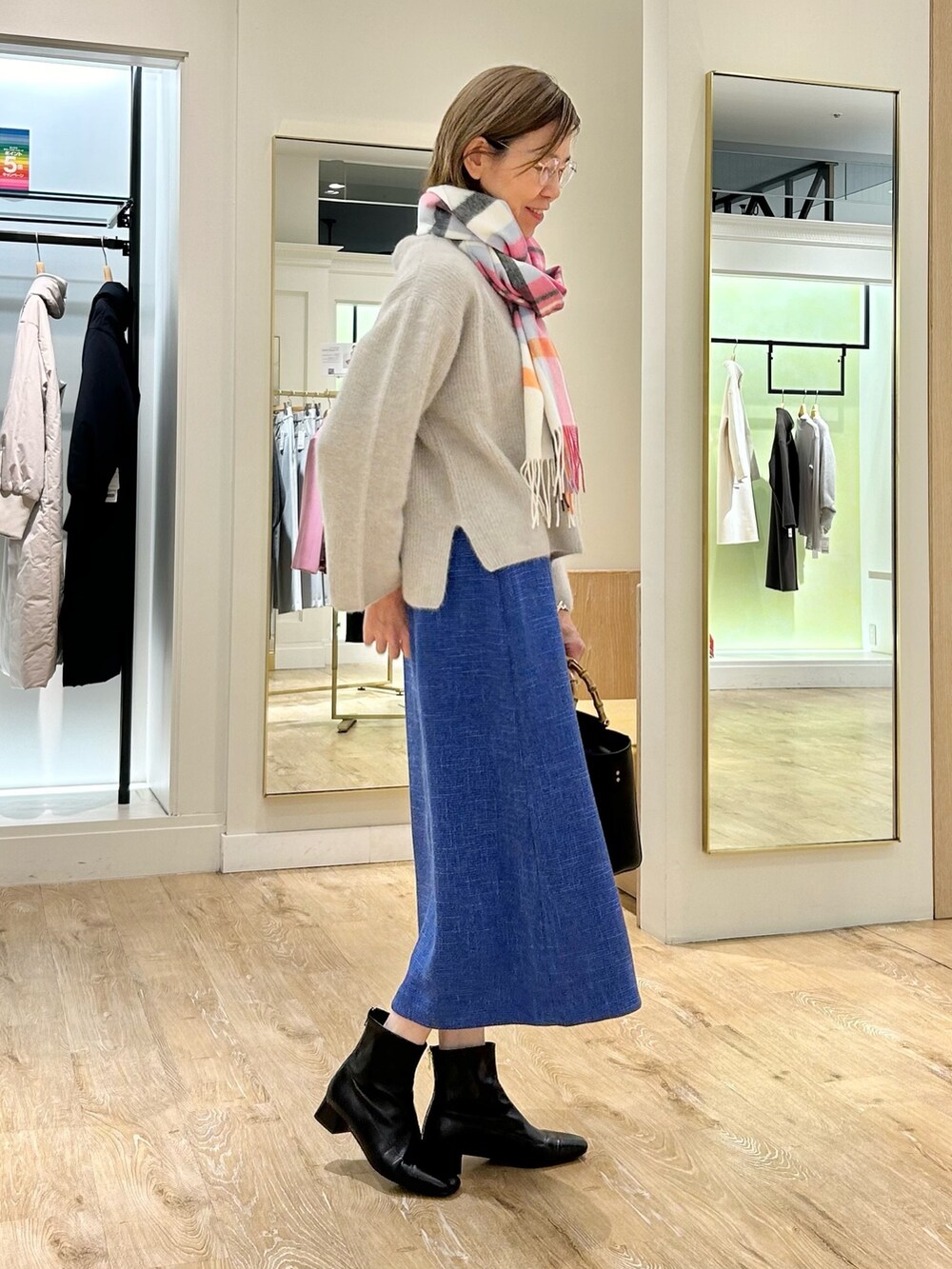 ブルー系のスカート、ブラック系のショルダーバッグ、ベージュ系のニット/セーターを着用したレディースの冬コーディネートの7枚目の写真