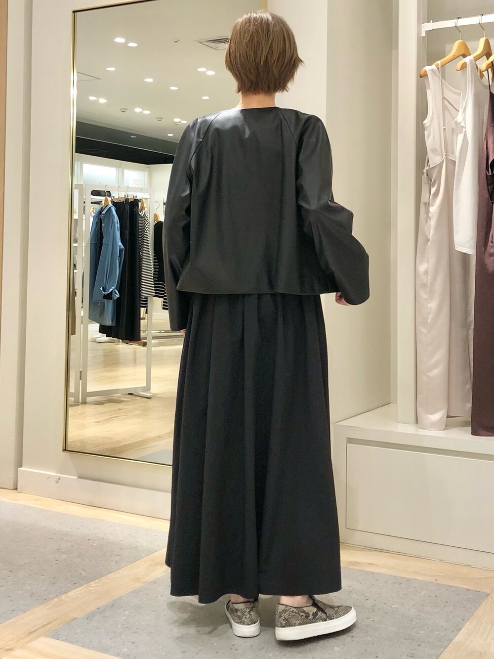 ブラック系のスカート、ブラック系のブルゾン、ホワイト系のTシャツ/カットソーを着用したレディースの夏コーディネートの6枚目の写真