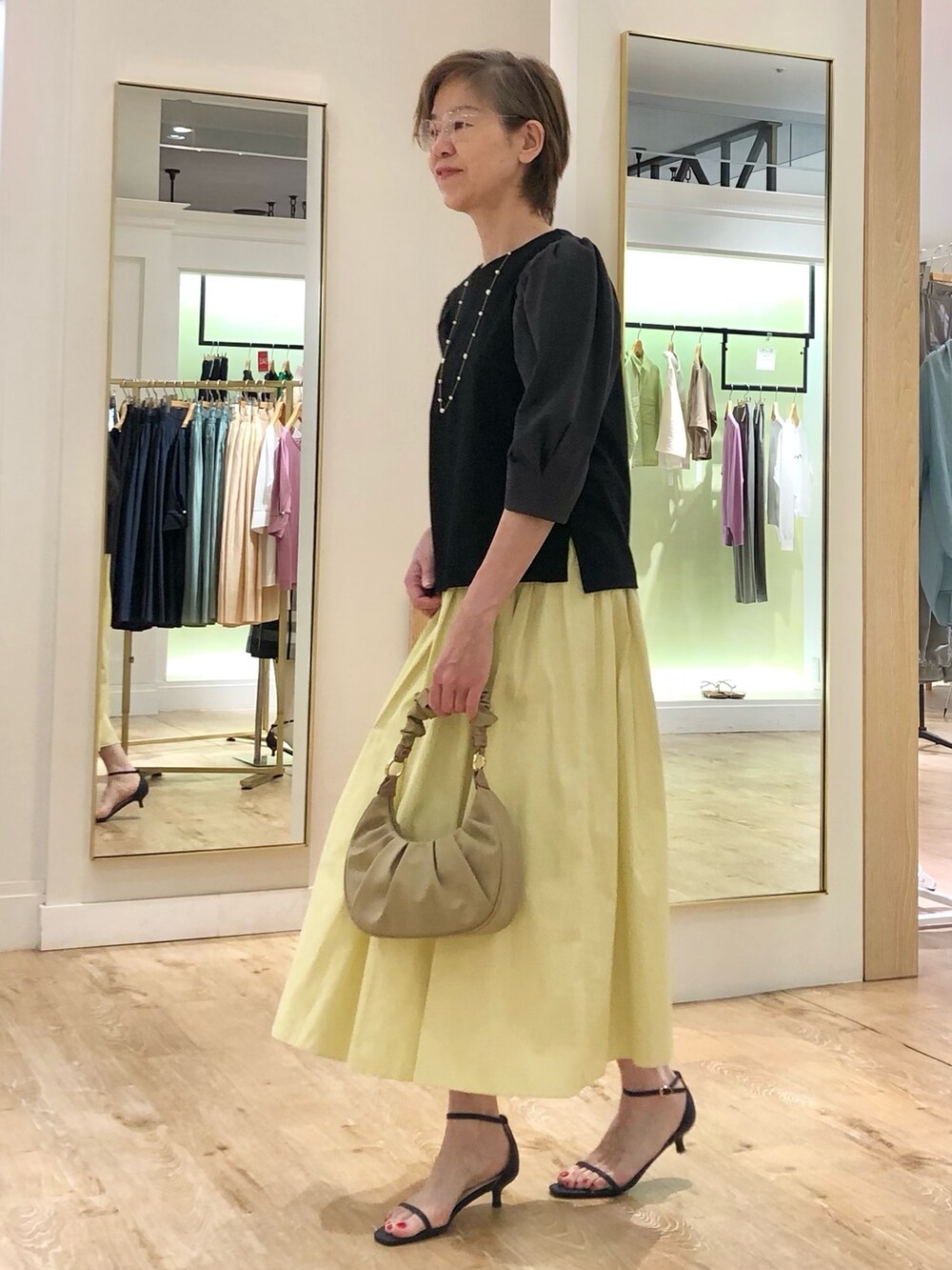 グレー系のTシャツ/カットソー、イエロー系のスカート、ベージュ系のショルダーバッグを着用したレディースの夏コーディネートの4枚目の写真