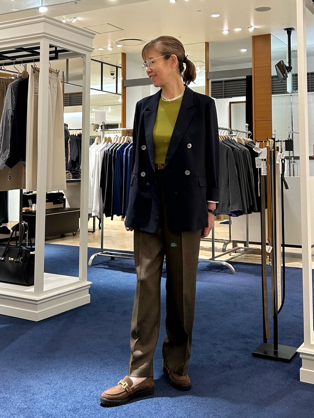 ブラウン系のその他パンツ、ブルー系のテーラードジャケット、グリーン系のニット/セーターを着用したレディースの秋コーディネートの2枚目の写真