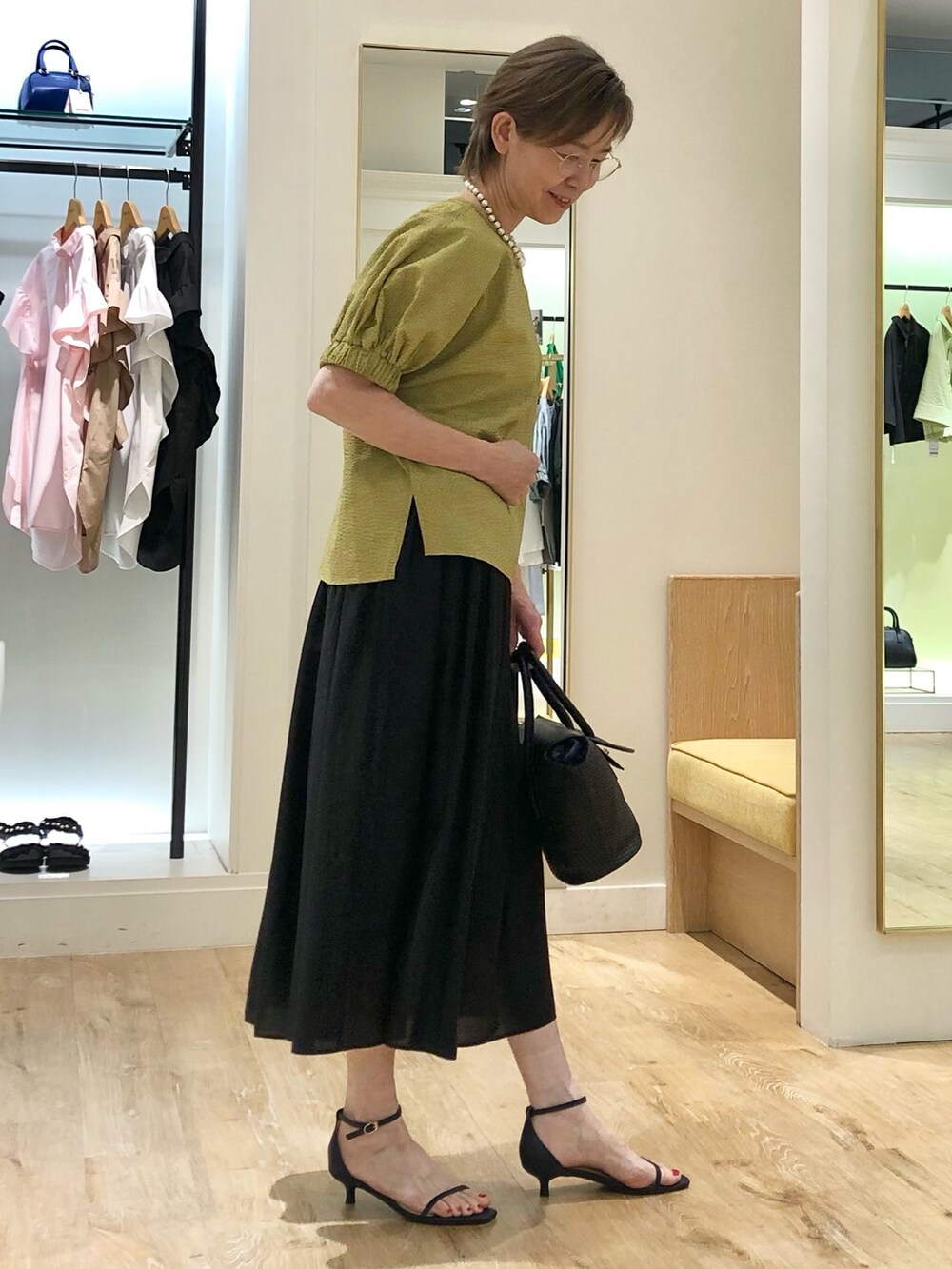 イエロー系のシャツ/ブラウス、ブラック系のスカート、ブラック系のかごバッグを着用したレディースの夏コーディネートの4枚目の写真