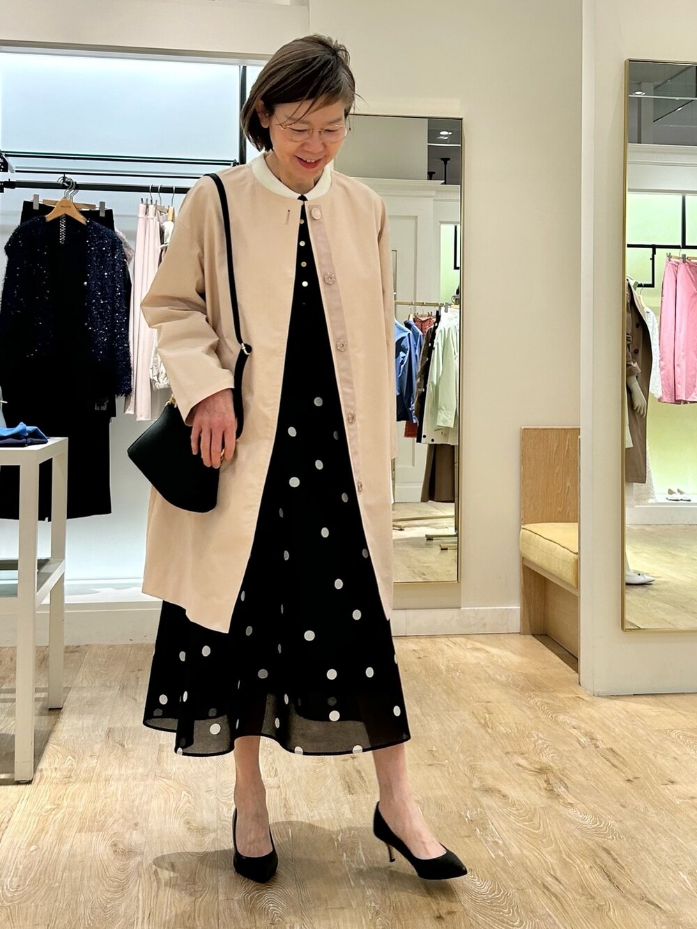 ブルー系のスカート、ピンク系のノーカラーコート、ブラック系のニット/セーターを着用したレディースの春コーディネートの3枚目の写真