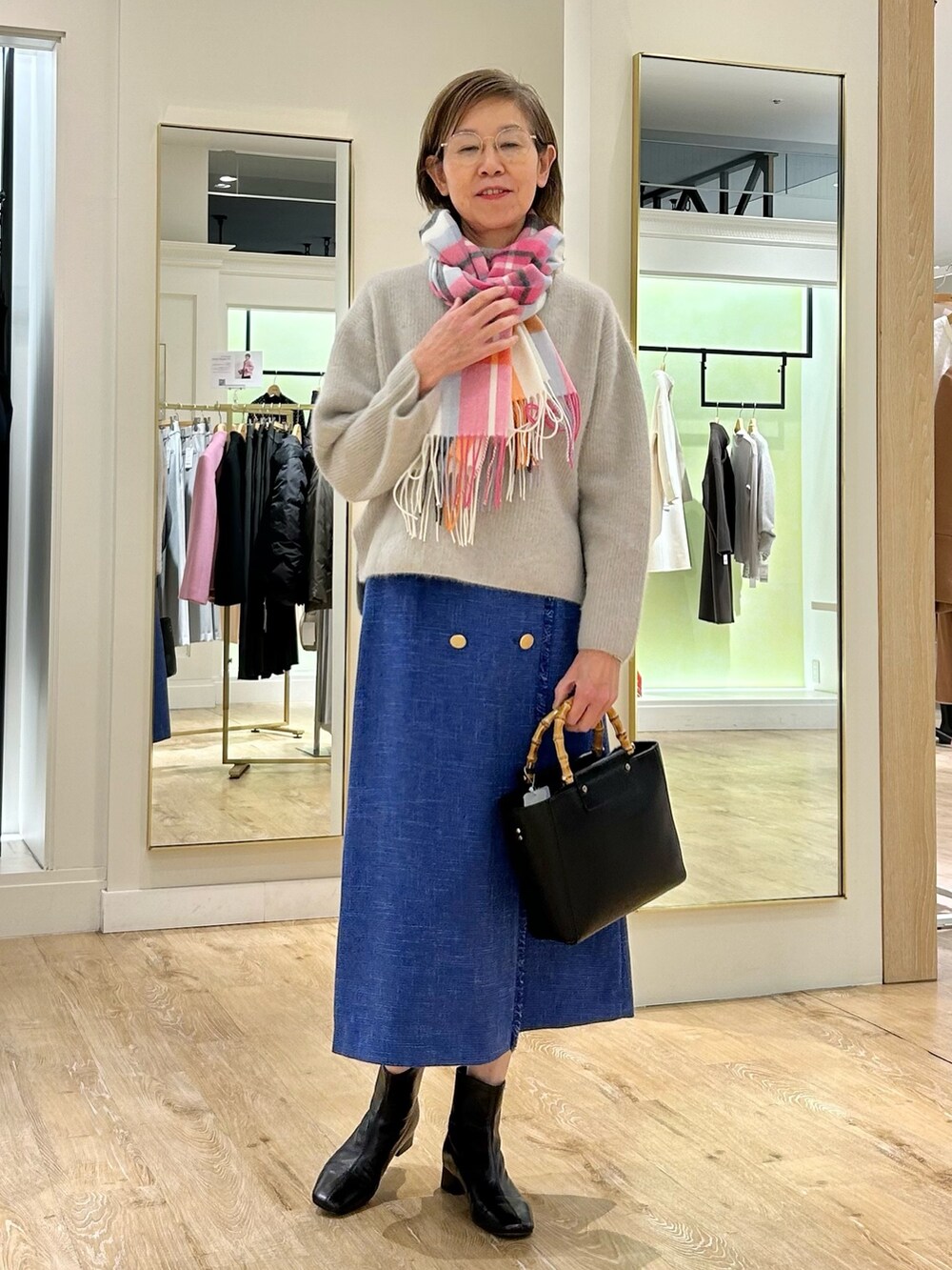 ブルー系のスカート、ブラック系のショルダーバッグ、ベージュ系のニット/セーターを着用したレディースの冬コーディネートの5枚目の写真