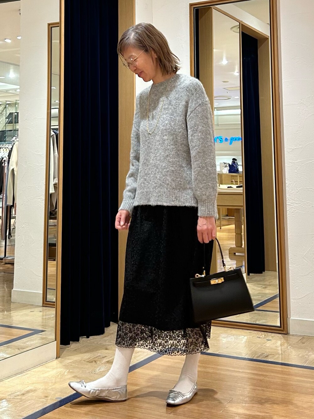 グレー系のニット/セーター、ブラック系のスカート、ブラック系のショルダーバッグを着用したレディースの冬コーディネートの6枚目の写真