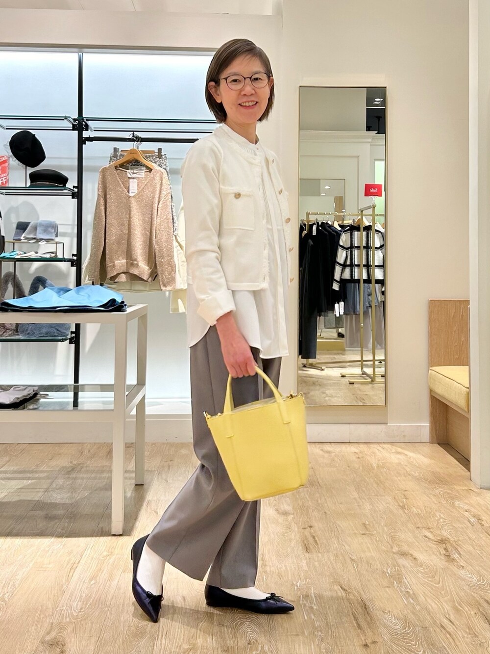 グレー系のその他パンツ、イエロー系のトートバッグ、ホワイト系のカーディガン/ボレロを着用したレディースの冬コーディネートの3枚目の写真