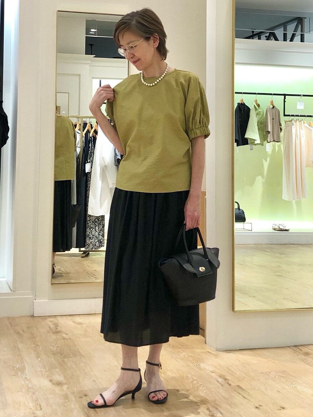 イエロー系のシャツ/ブラウス、ブラック系のスカート、ブラック系のかごバッグを着用したレディースの夏コーディネートの2枚目の写真