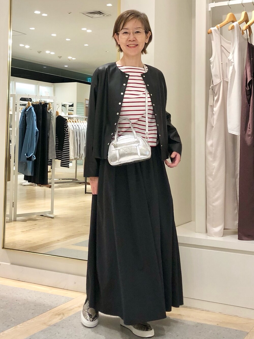 ブラック系のスカート、ブラック系のブルゾン、ホワイト系のTシャツ/カットソーを着用したレディースの夏コーディネートの3枚目の写真