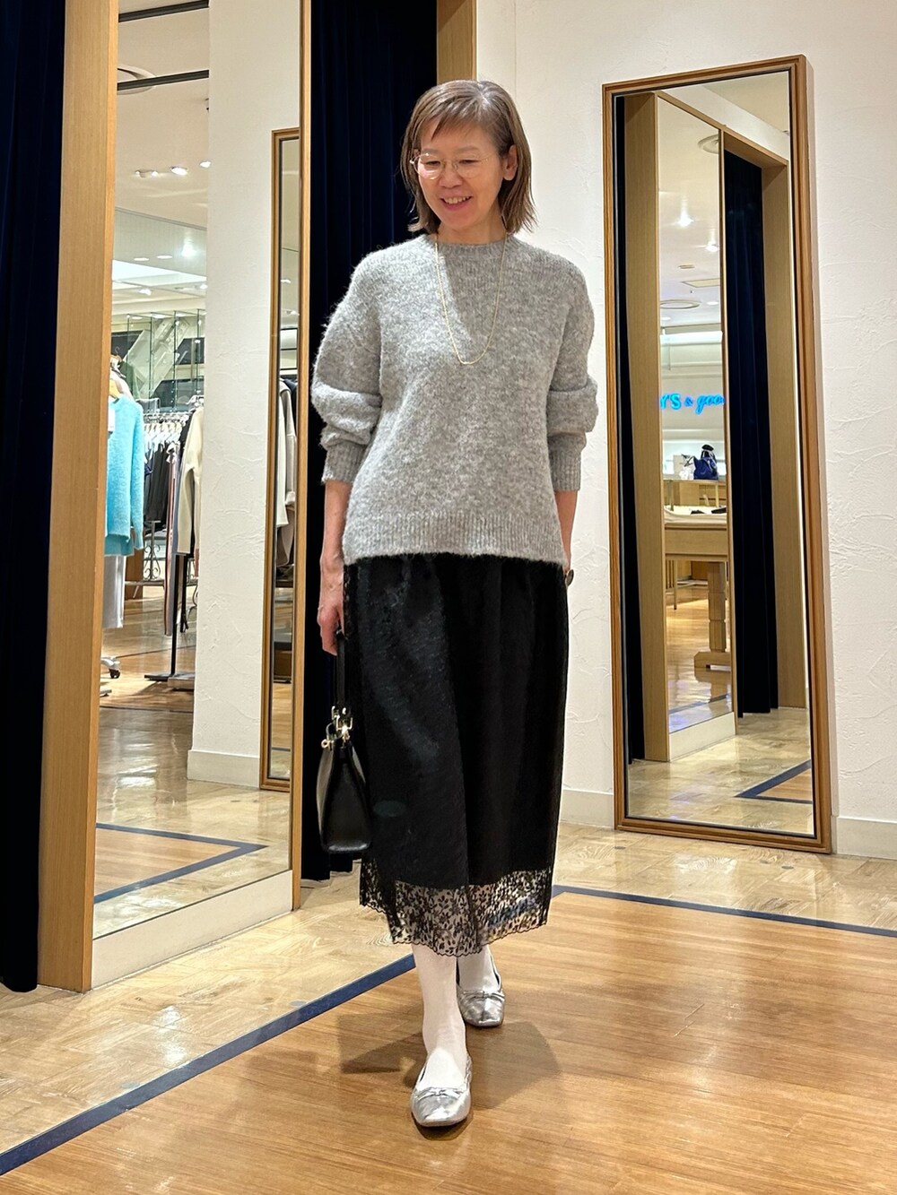 グレー系のニット/セーター、ブラック系のスカート、ブラック系のショルダーバッグを着用したレディースの冬コーディネートの5枚目の写真