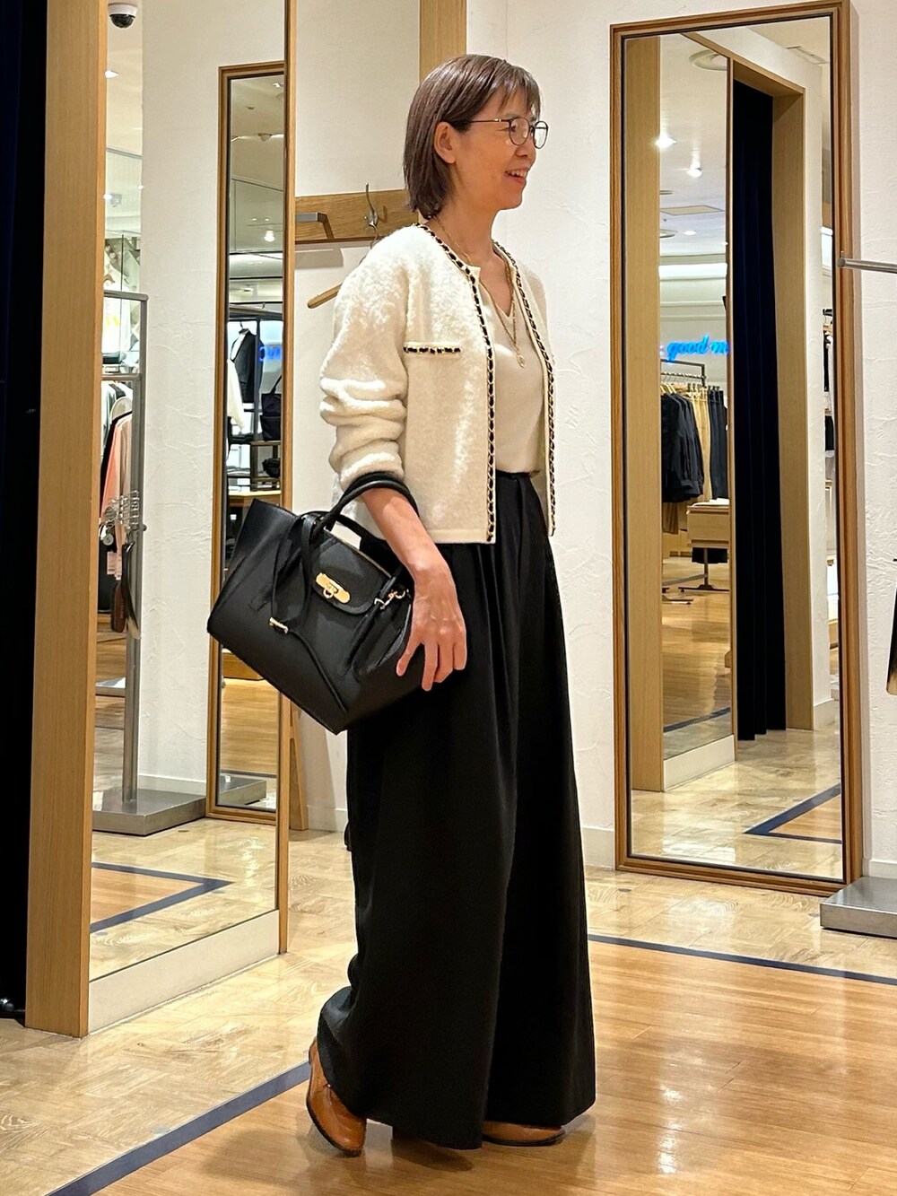 ブラック系のその他パンツ、ブラック系のショルダーバッグ、ホワイト系のカーディガン/ボレロを着用したレディースの秋コーディネートの2枚目の写真