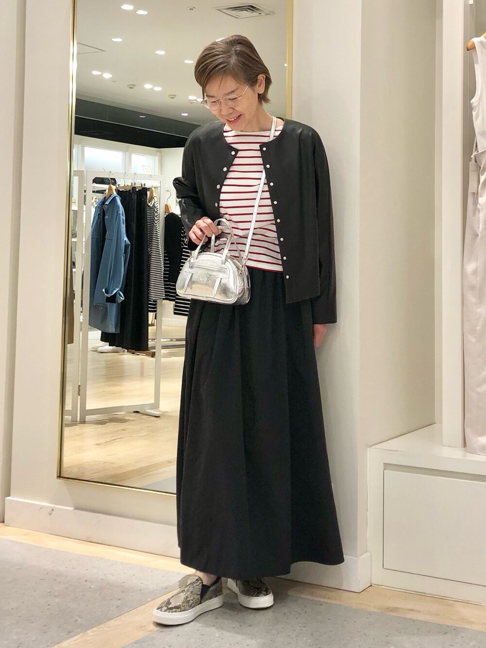 ブラック系のスカート、ブラック系のブルゾン、ホワイト系のTシャツ/カットソーを着用したレディースの夏コーディネートの2枚目の写真