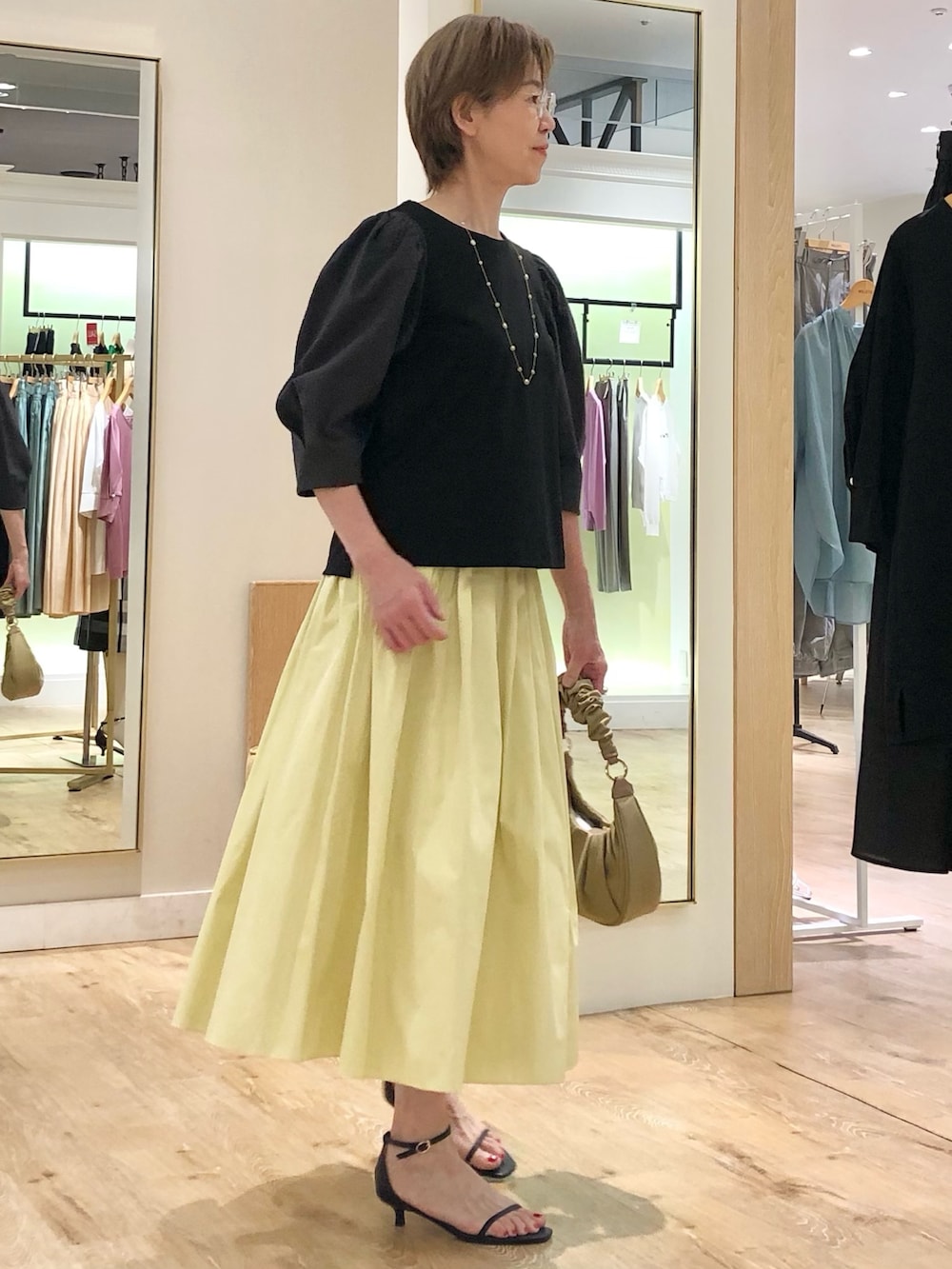 グレー系のTシャツ/カットソー、イエロー系のスカート、ベージュ系のショルダーバッグを着用したレディースの夏コーディネートの3枚目の写真