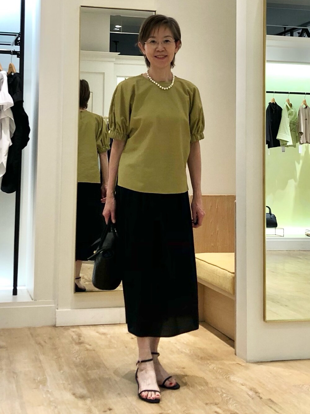 イエロー系のシャツ/ブラウス、ブラック系のスカート、ブラック系のかごバッグを着用したレディースの夏コーディネートの3枚目の写真